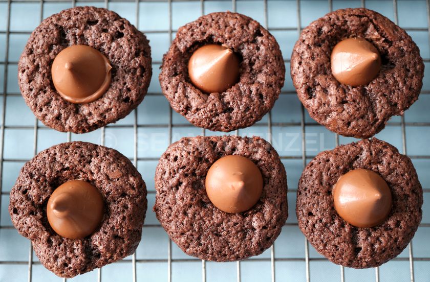 Mini-brownies with Hershey's Kiss chocolate candies pressed into the middle on a cooling rack. 